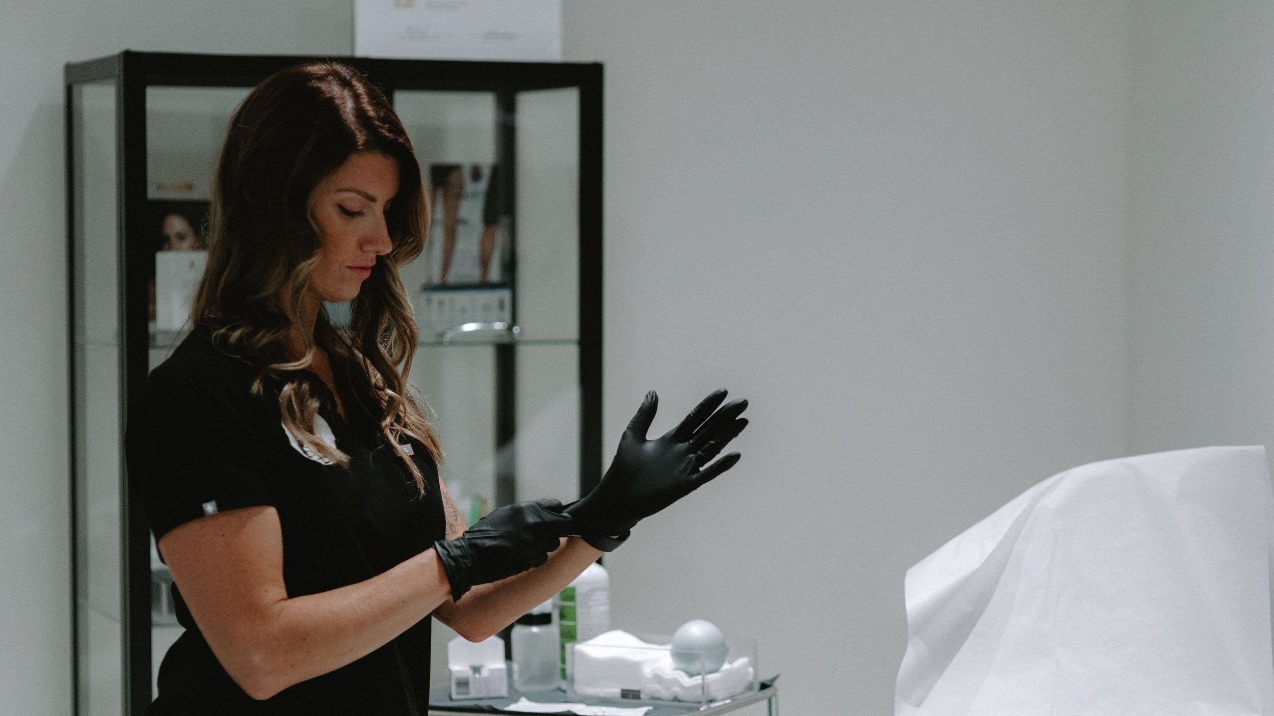 A woman wearing black gloves, preparing for a Belkyra treatment.