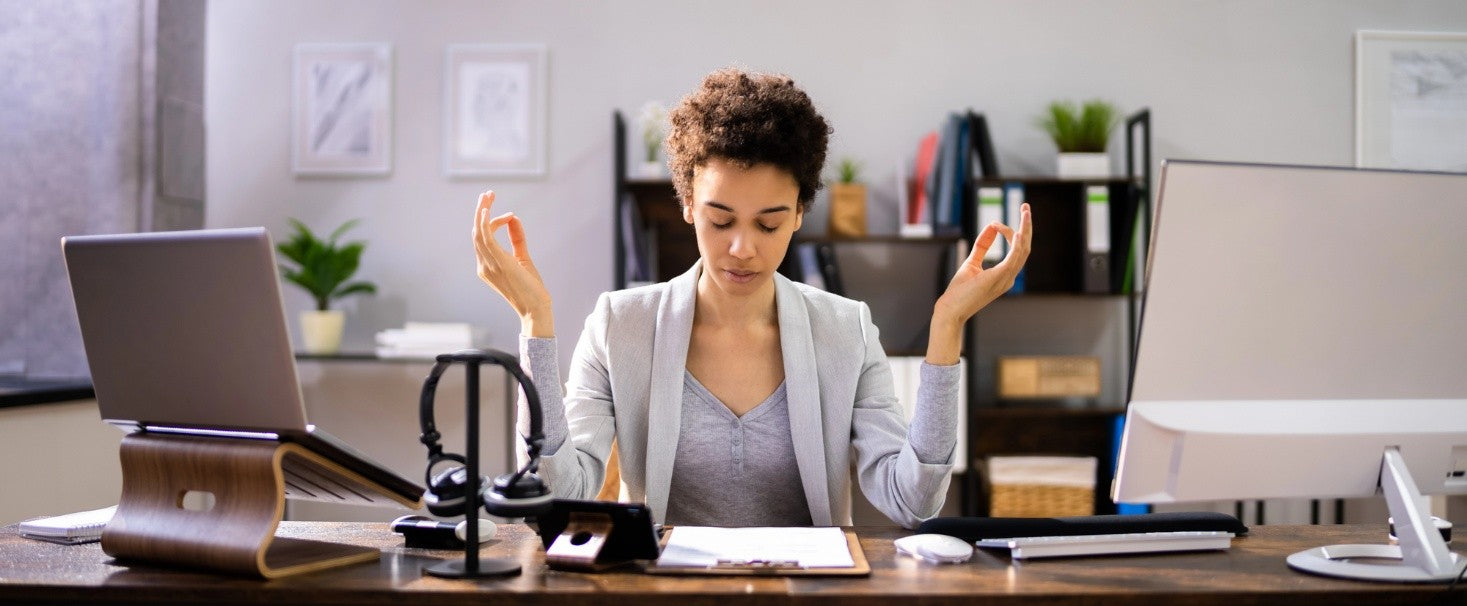 A self-assured woman is taking a moment at work to align her focus.