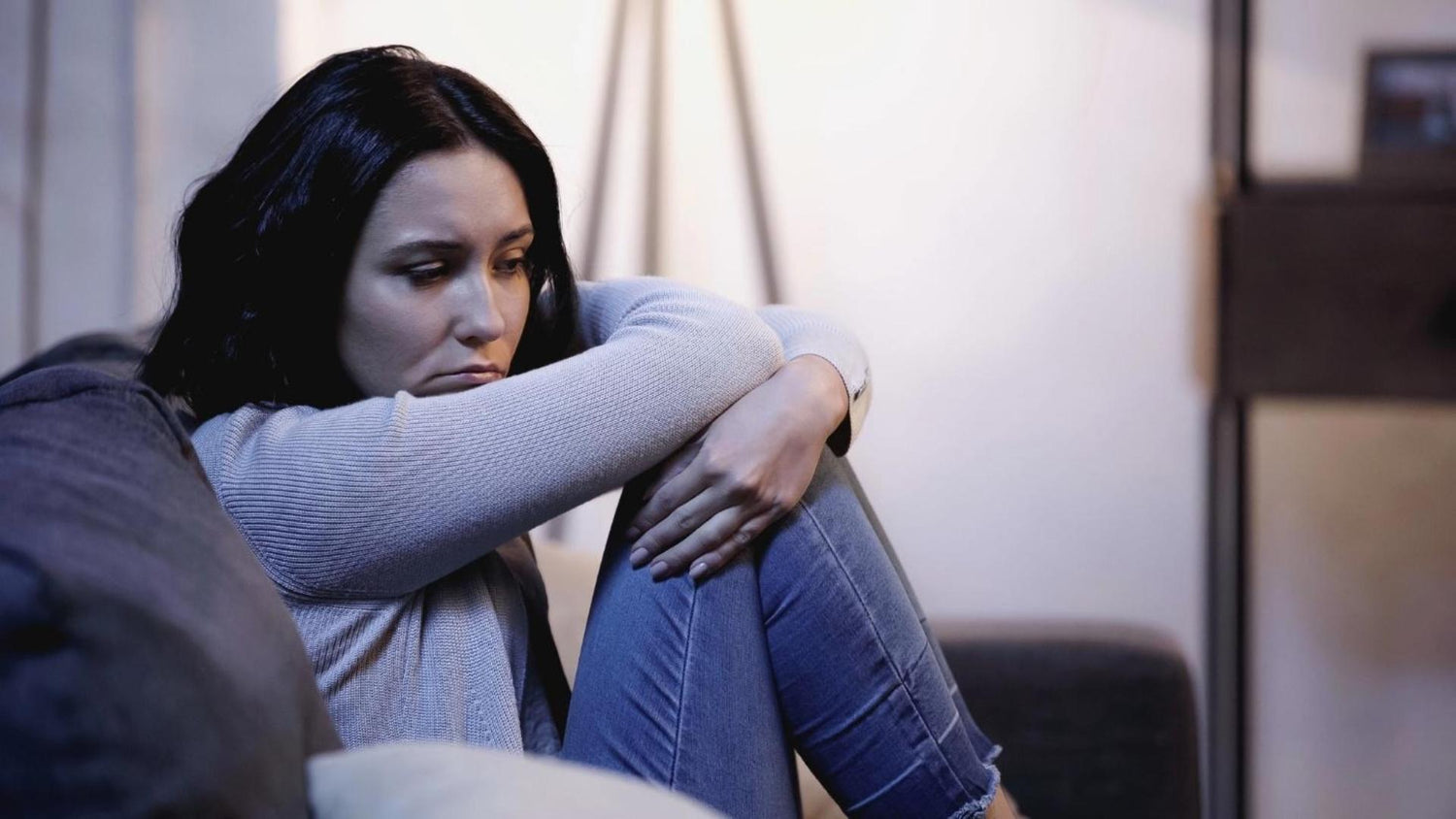 A depressed woman sitting on a couch.